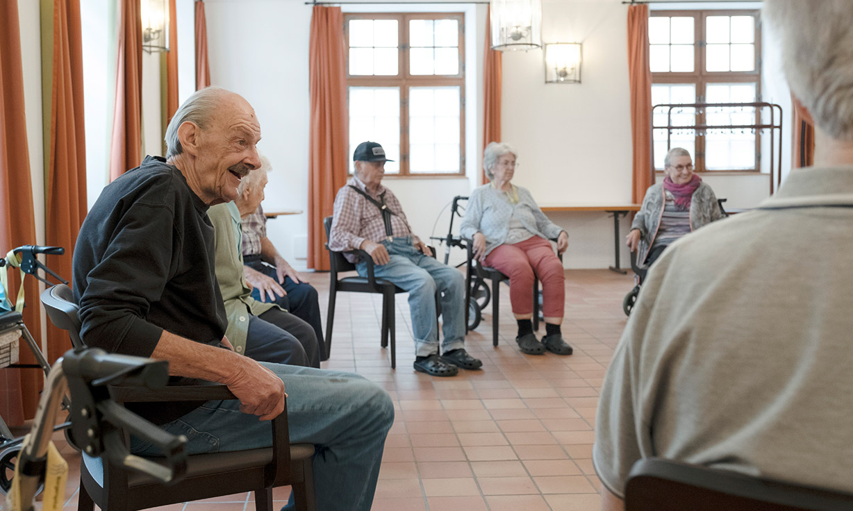 Zufriedene Senioren sitzen auf Stühlen zusammen in einem Kreis