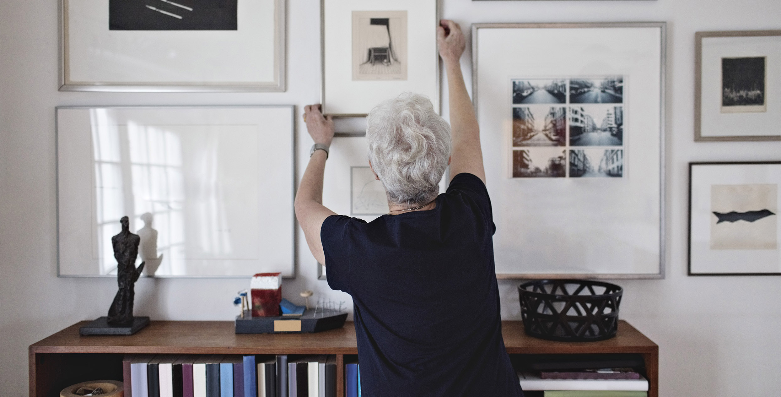 Seniorin richtet ein Zimmer mit Bilder ein 