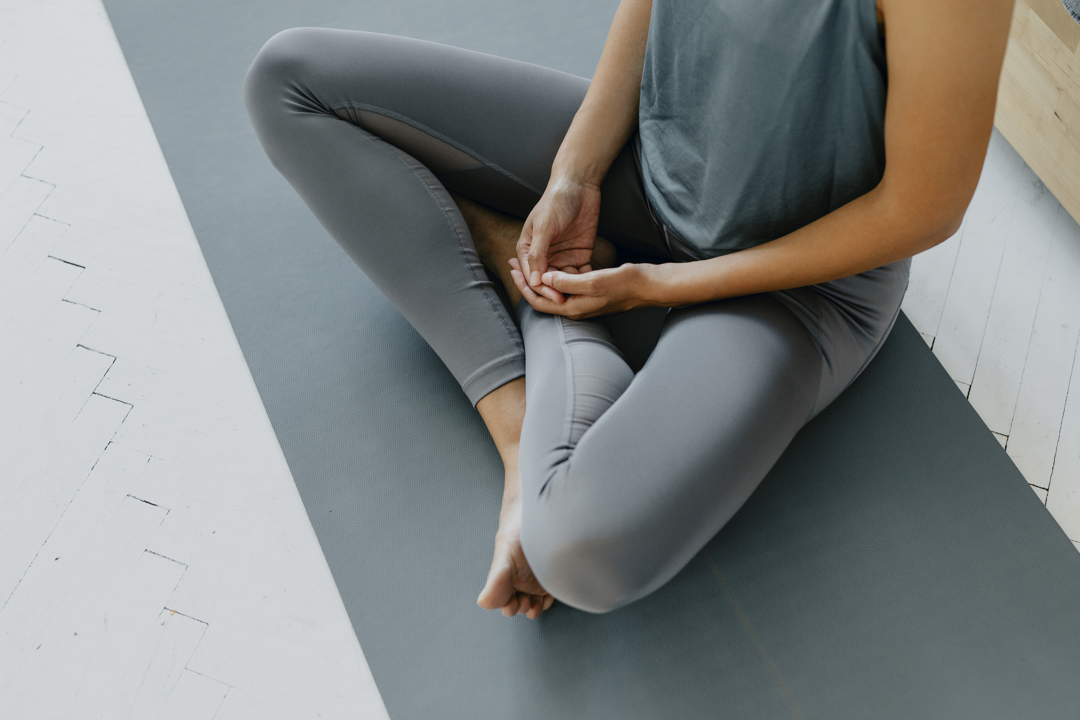 Das Gesundheitsprogramm namens "Xund und Vital" fördert die Gesundheit der Mitarbeitenden. Person im Schneidersitz (Sukhasana) auf einer grauen Matte.