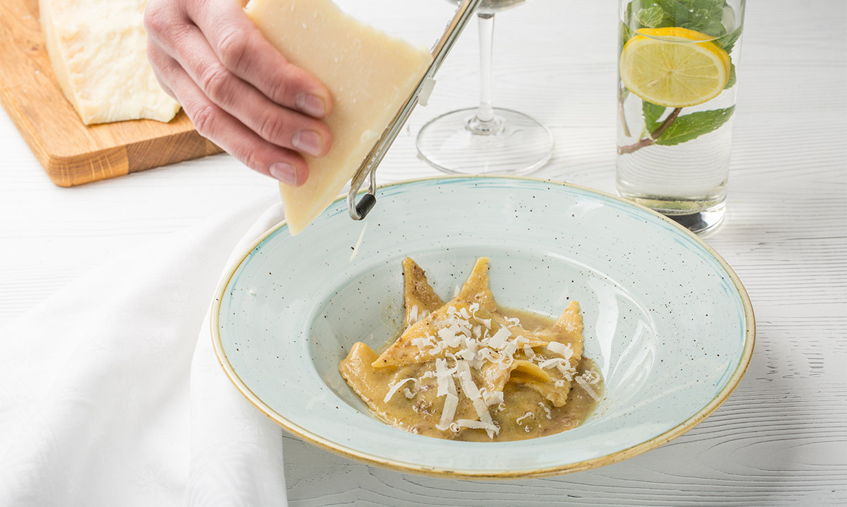 Käse wird über die Pasta gerieben