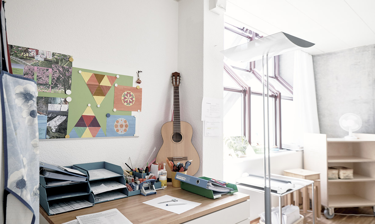 Heller Raum mit einer Gitarre, Bildern an der Wand und einem Schreibtisch