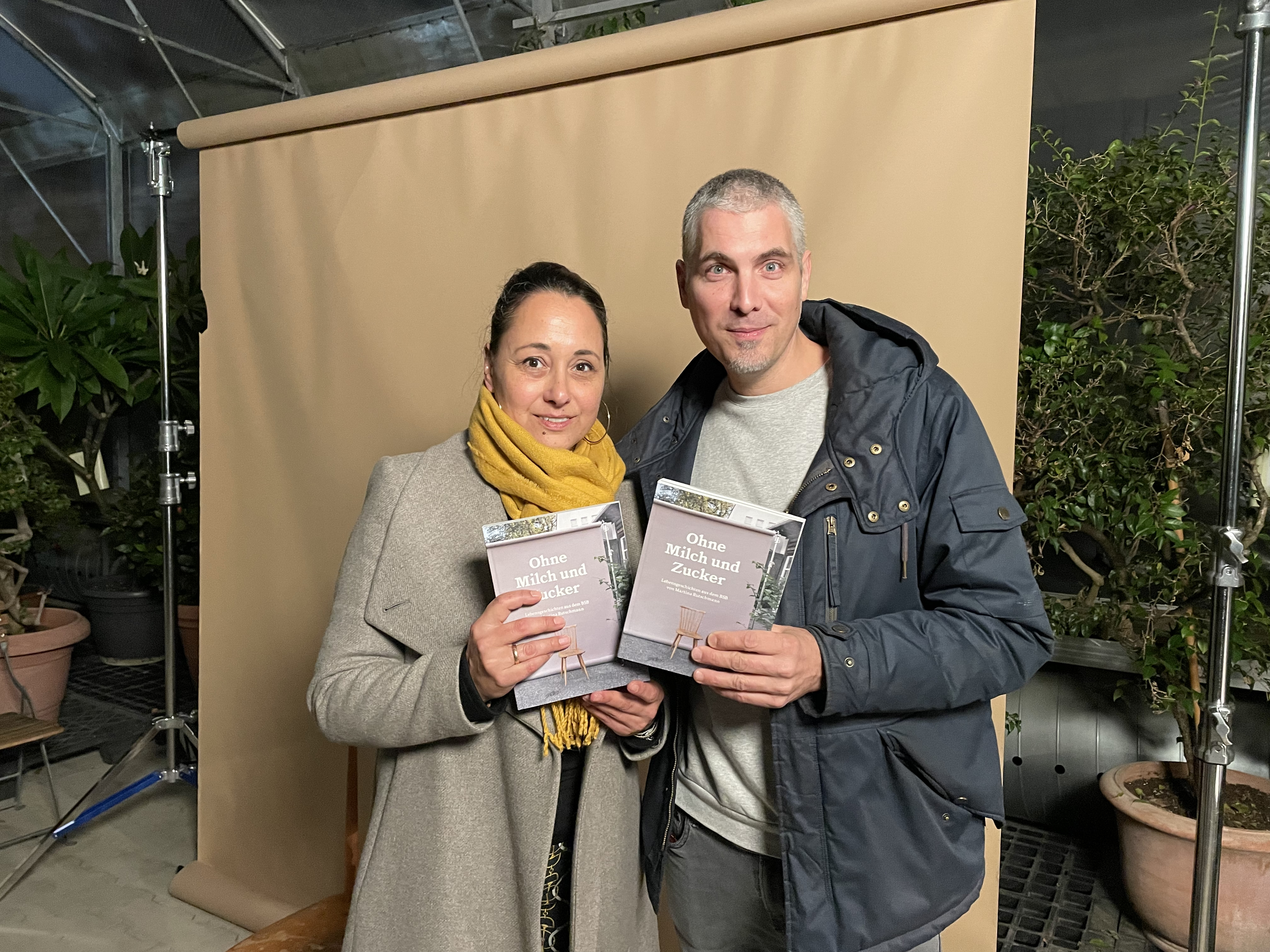 Ein Foto von Autorin Martina Rutschmann mit Fotograf Jean Weber, beide halten ein Exemplar von 'Ohne Milch und Zucker' in den Händen