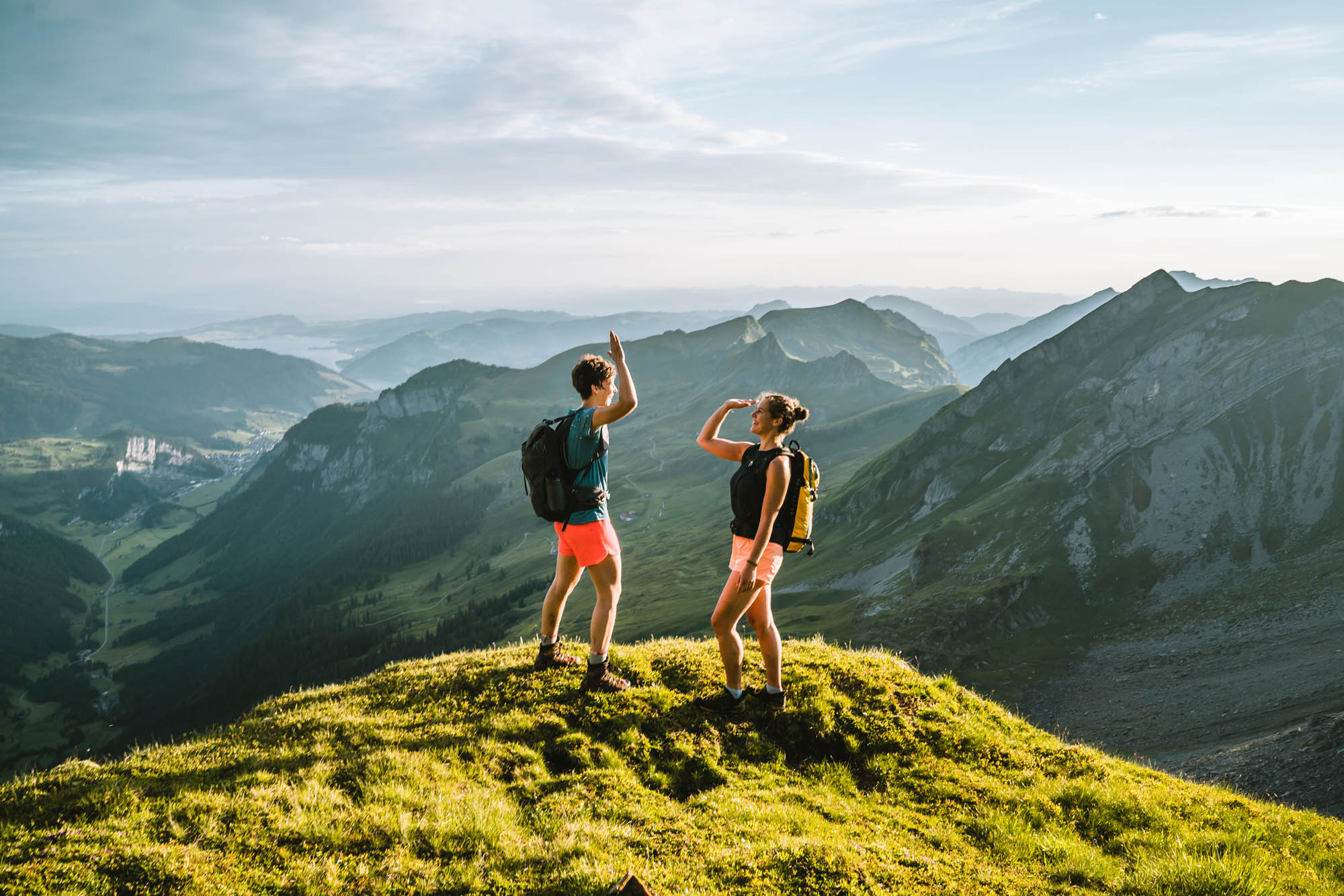 Zwei Personen stehen auf einem Berg und geben sich High Five