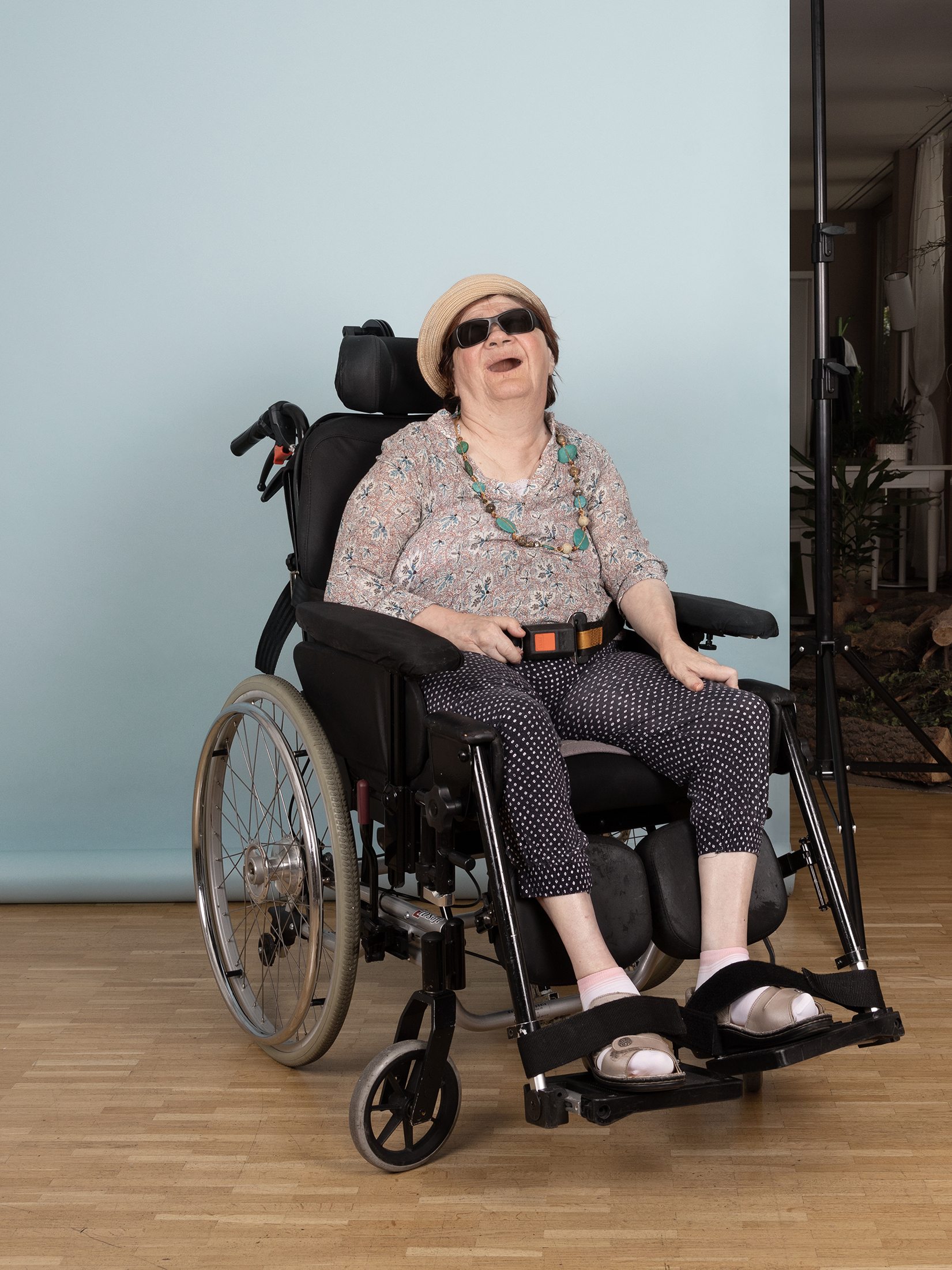 Ein Foto aus dem Buch "Ohne Milch und Zucker". Heidi sitzt in einem Rollstuhl vor einer hellblauen Leinwand.