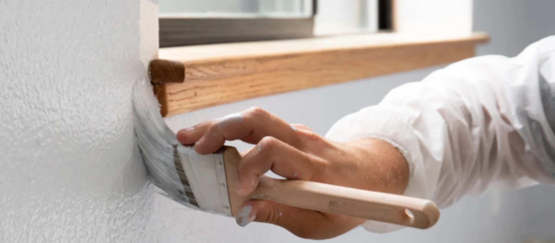 Das Foto zeigt die Hand einer Person, die gerade eine Wand streicht.