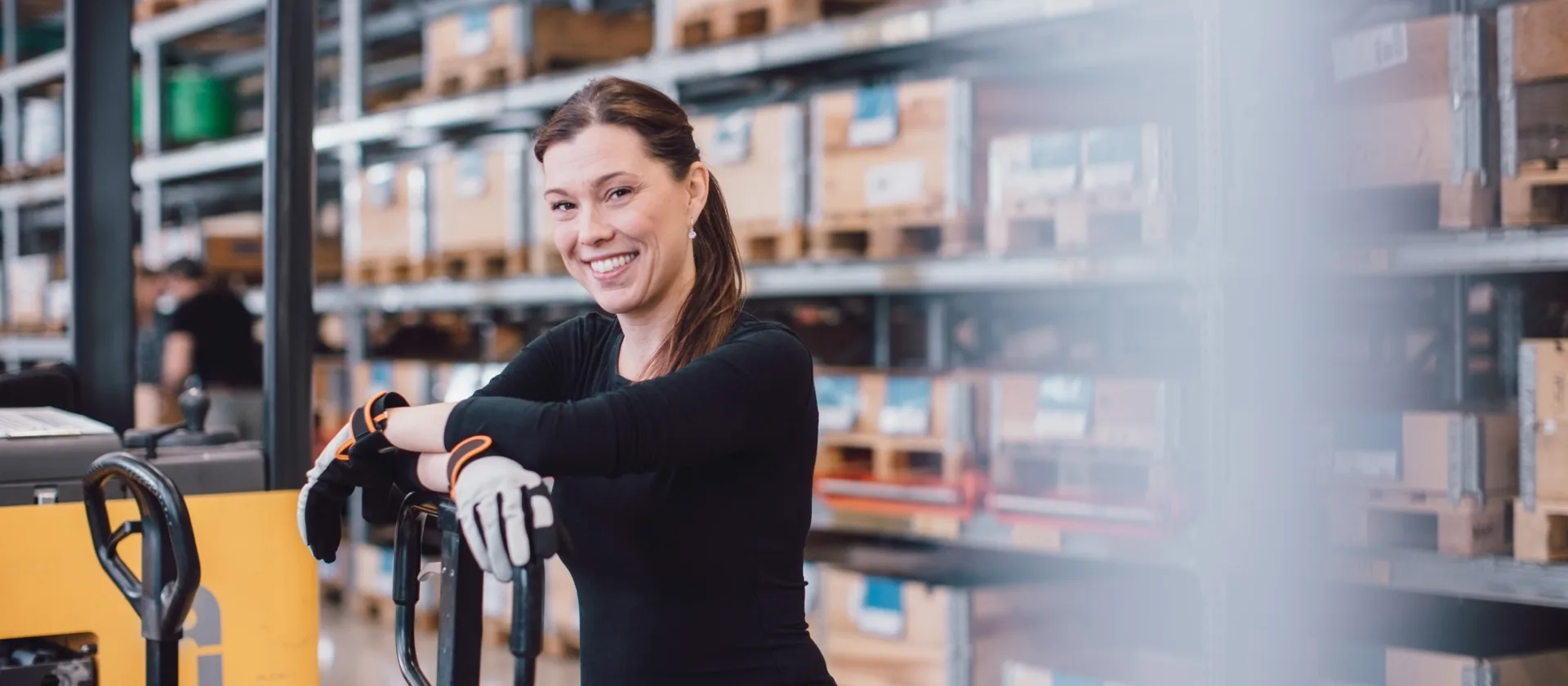 Eine Person, die sich an einen Gabelstapler lehnt und in die Kamera lächelt.