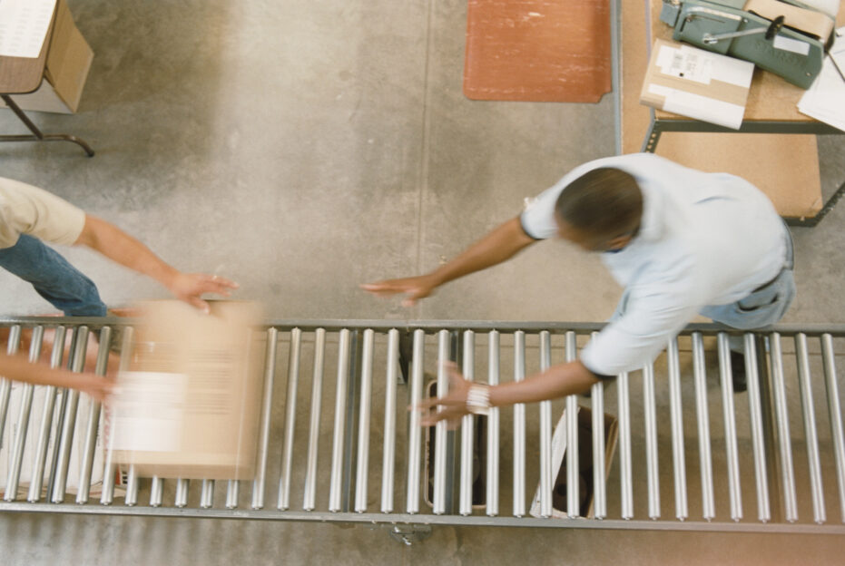 Zwei Personen, die sich etwas über das Rollband zuschicken.