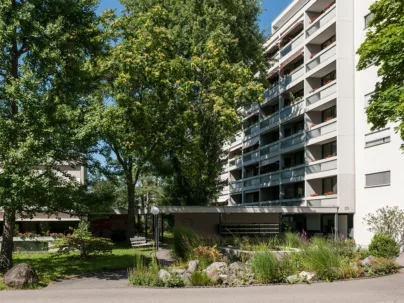 Ein Garten mit Bäumen zwischen den Gebäuden der Alterswohnungen Gellertfeld