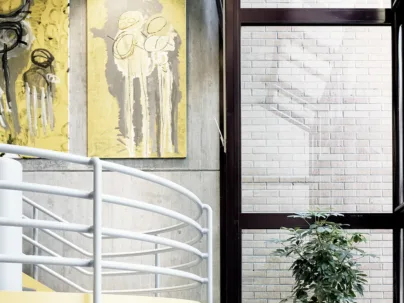 Ein Treppenhaus mit zwei gelben Kunstwerken an der Wand und einer Zimmerpflanze