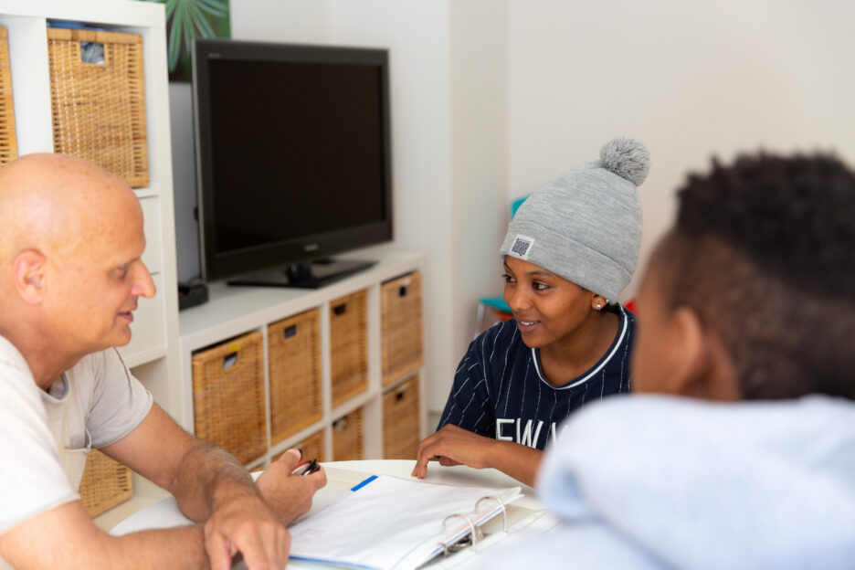 Drei Personen sitzen an einem Tisch und besprechen miteinander
