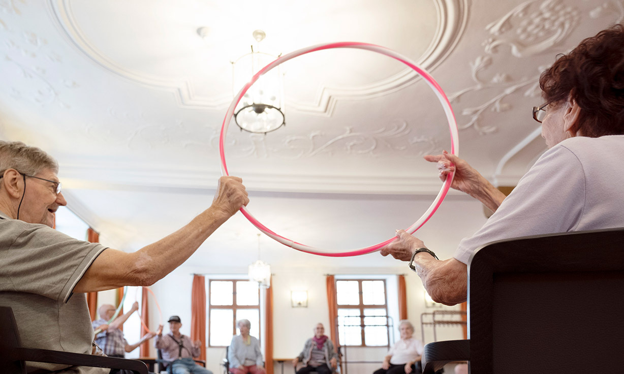 Zufriedene Senioren unternehmen eine Aktivität mit einem Hula Hoop Reifen