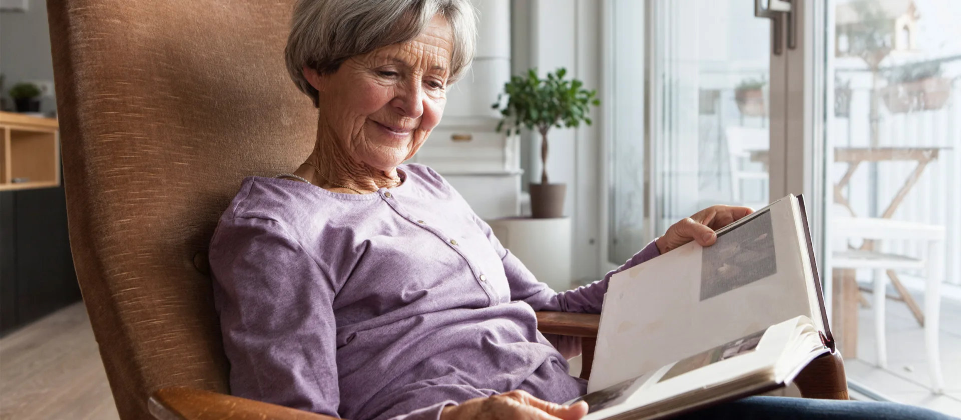 Seniorin im Sessel schaut sich ein Fotoalbum an