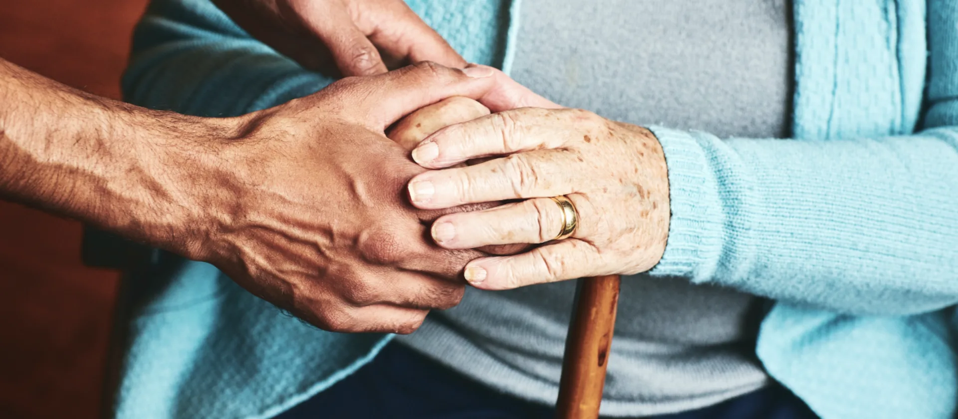 Seniorin hält einen Gehstock und kriegt Unterstützung