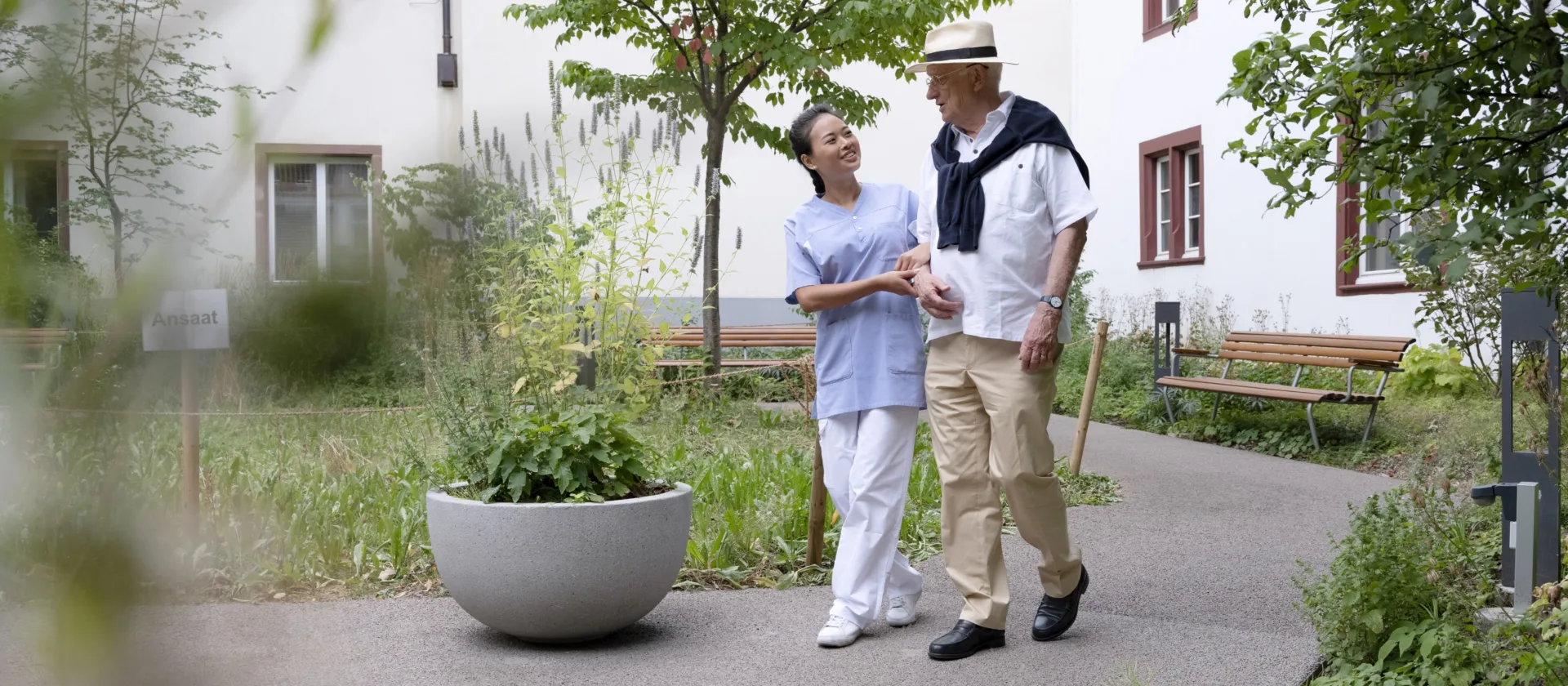 Pflegerin und Senior bei einem Spaziergang im Grünen