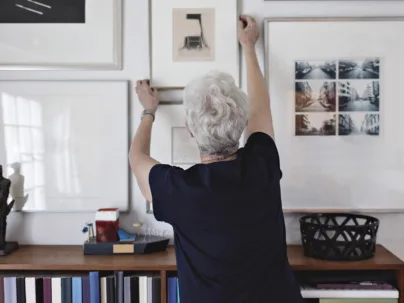 Seniorin richtet ein Zimmer mit Bilder ein