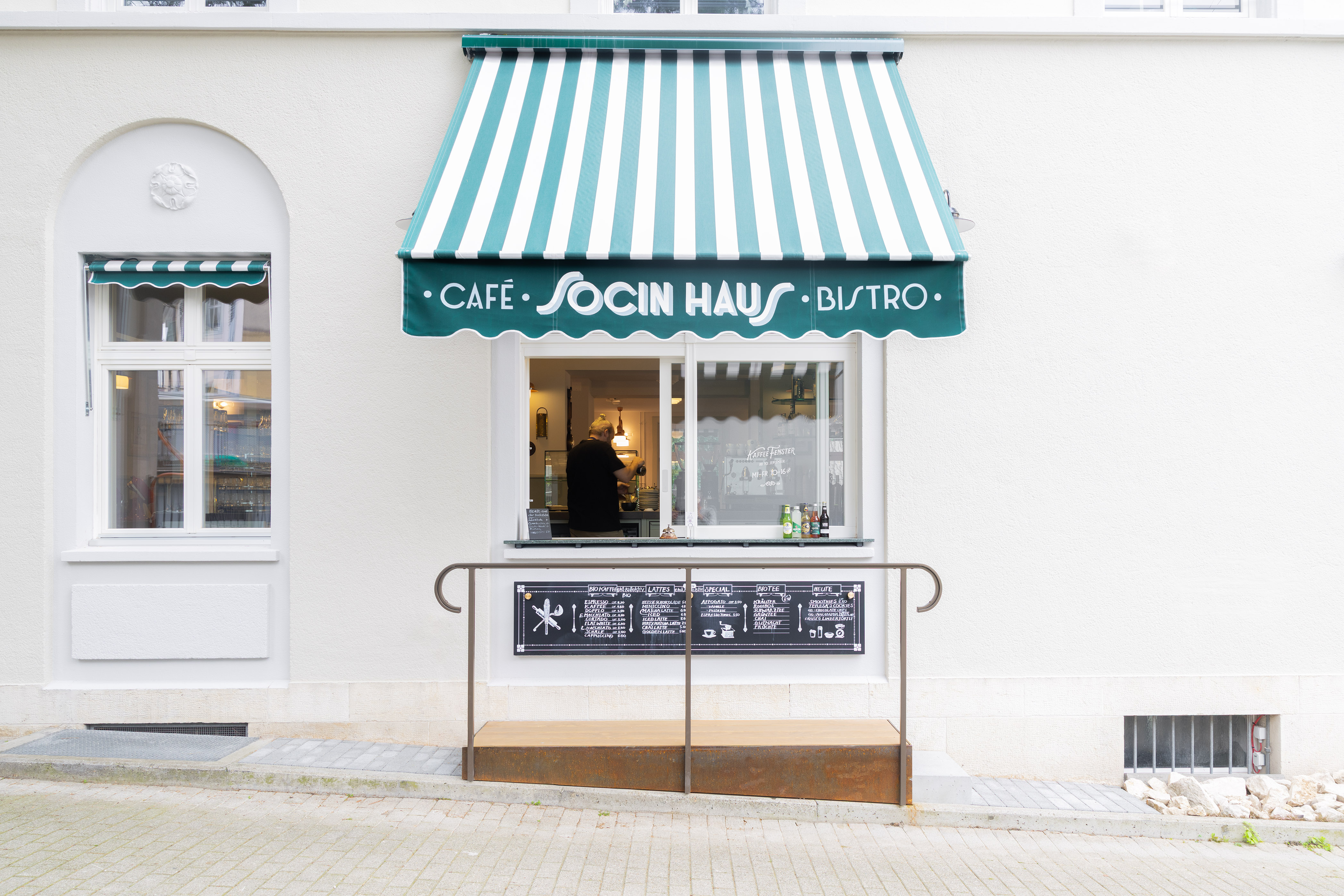 Aussenansicht des Kaffeefensters, offene, gestreifte Storen